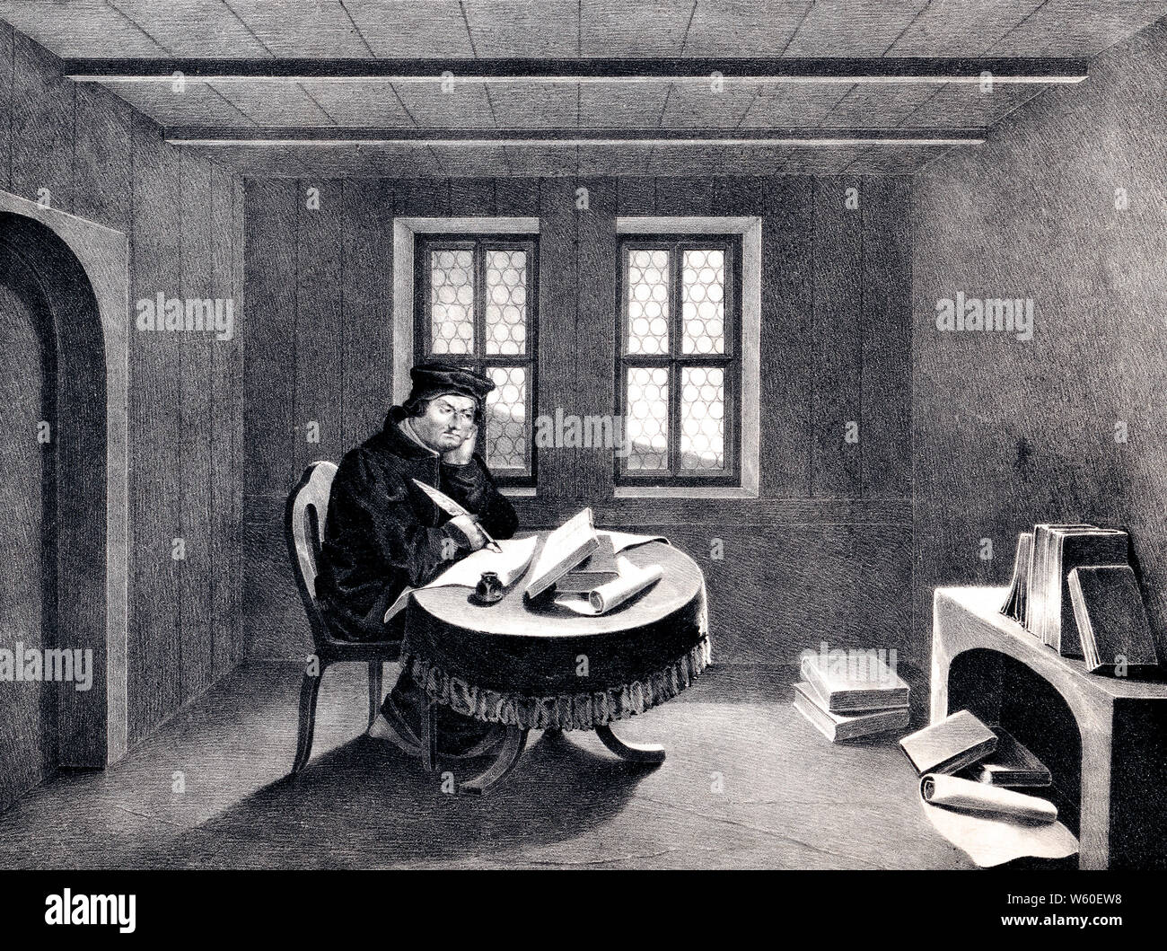 Print shows Martin Luther seated at a table in his room at the Wartburg castle, possibly translating the New Testament from the original Greek into German. Stock Photo