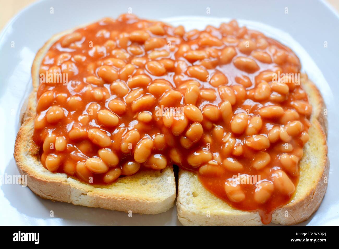 Baked beans in tomato sauce on thick white toast served on a white plate Stock Photo