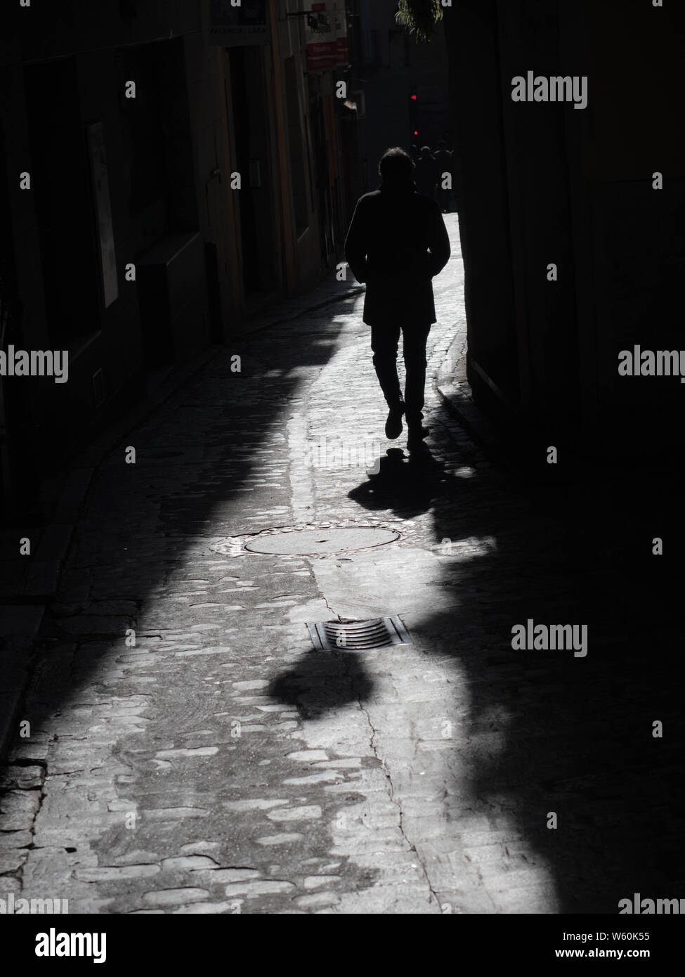 Man walking on street between shadows. Hombre caminando entre sombras Stock Photo