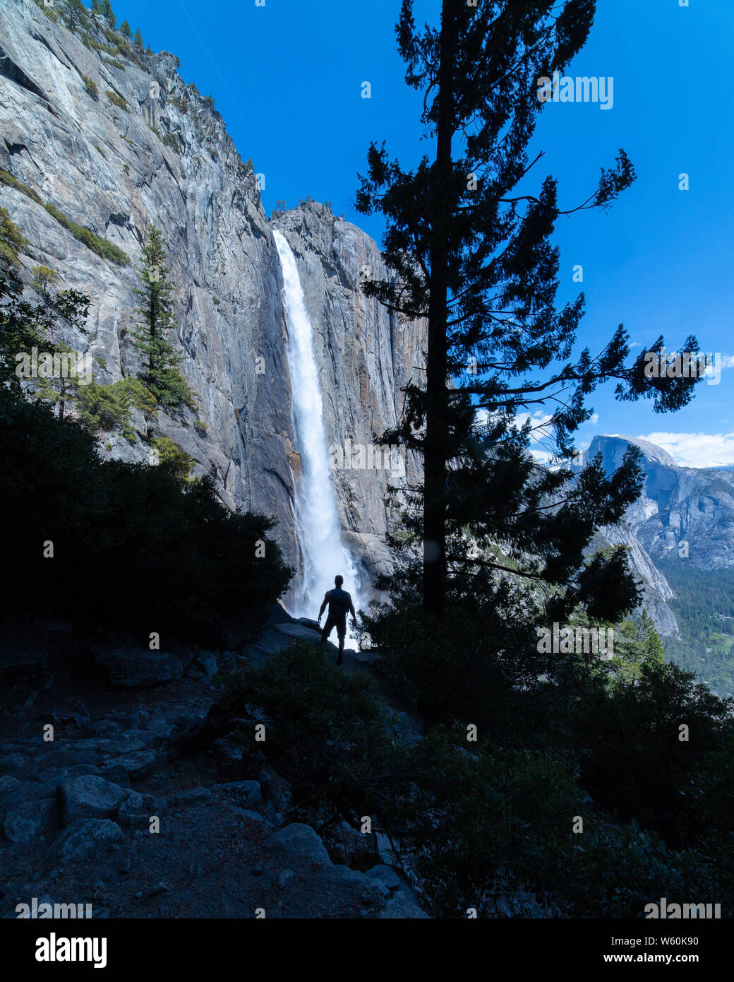 Man standing silhouetted in front of massive waterfall. Stock Photo