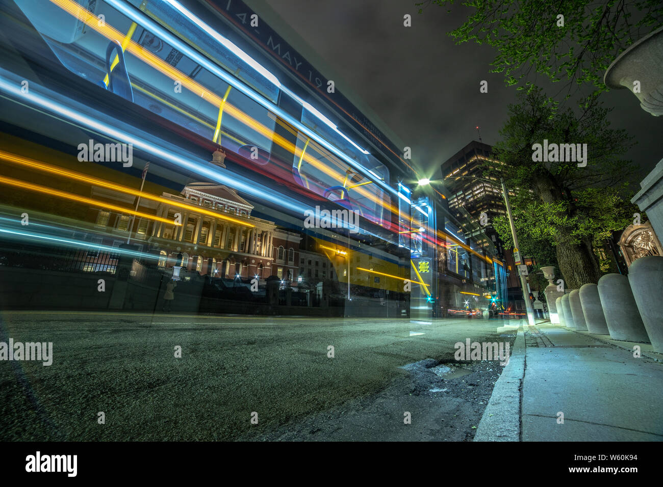 Long exposure city bus lights passing by State House building. Stock Photo