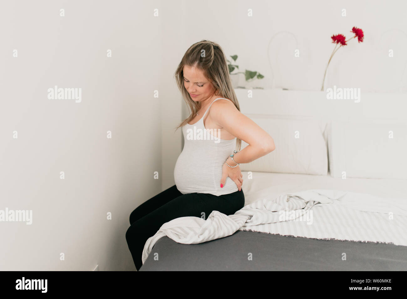pregnant woman sitting on the edge of the bed with backache Stock Photo Alamy