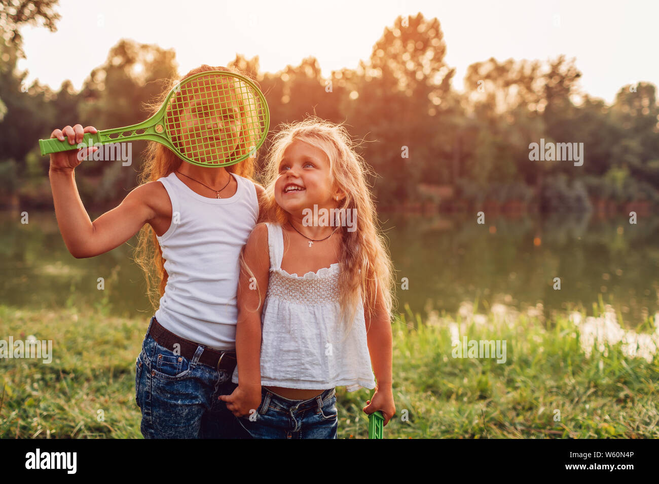 Little girl playing badminton with sister in summer park. Kids having fun outdoors. Close up of shuttlecock and racket Stock Photo
