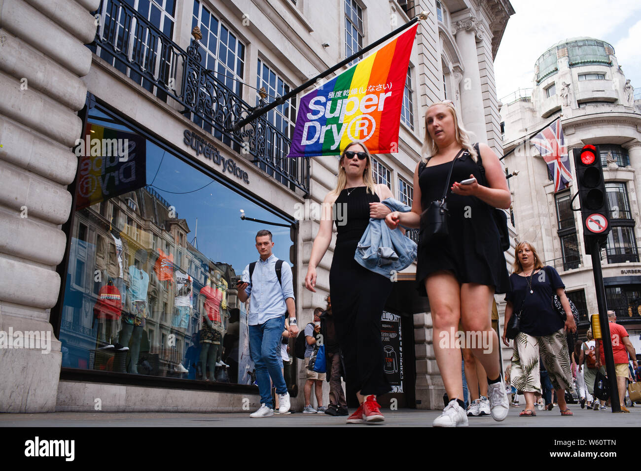 July 5, 2019, London, United Kingdom: Shoppers walk past a Pride-themed,  rainbow-coloured flag on display outside the flagship branch of clothing  retailer Superdry on Regent Street in central London.This year marks the
