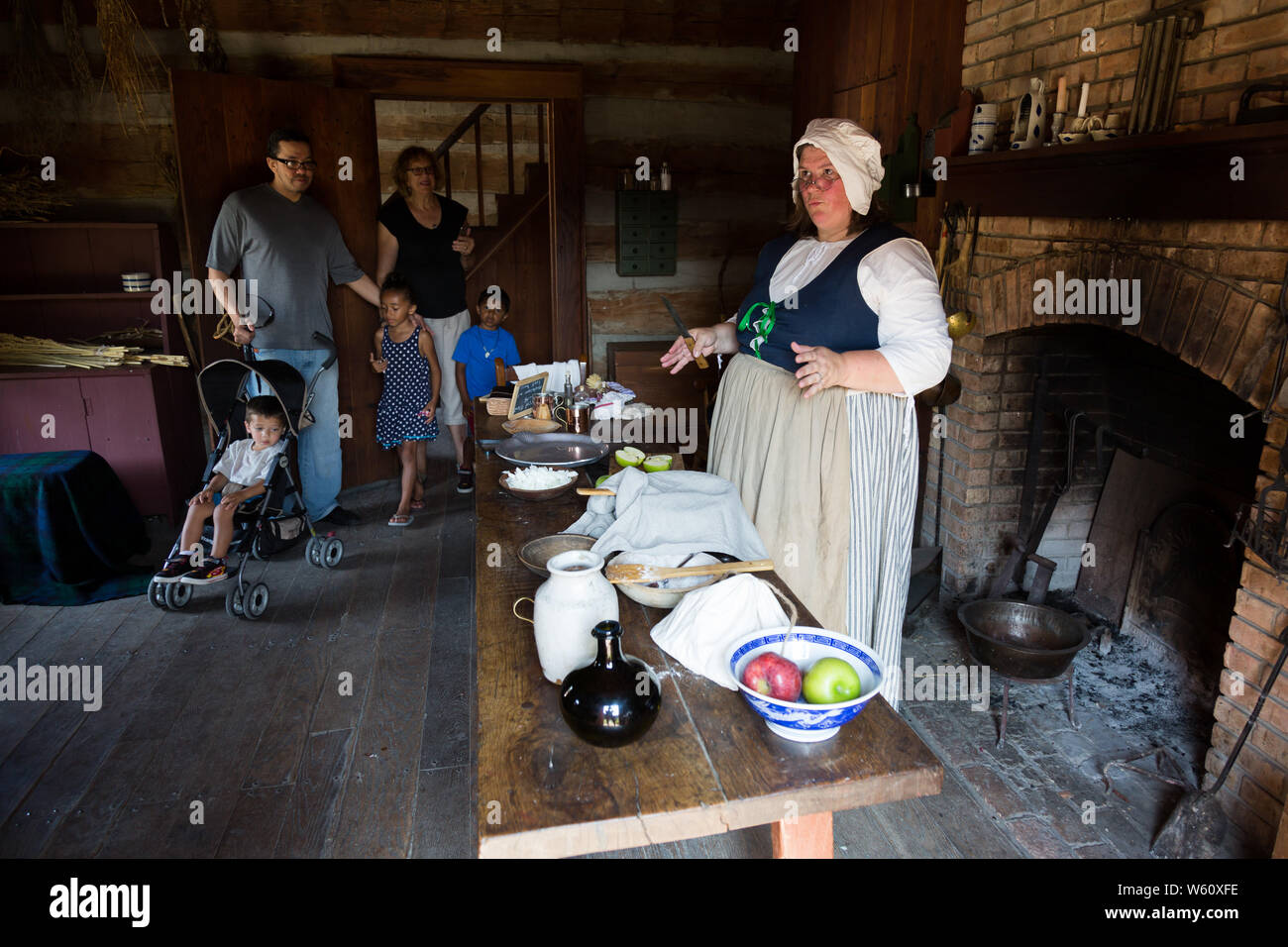 A family walks in as a reenactress demonstrates cooking techniques during an event at Historic Old Fort Wayne in Fort Wayne, Indiana, USA. Stock Photo