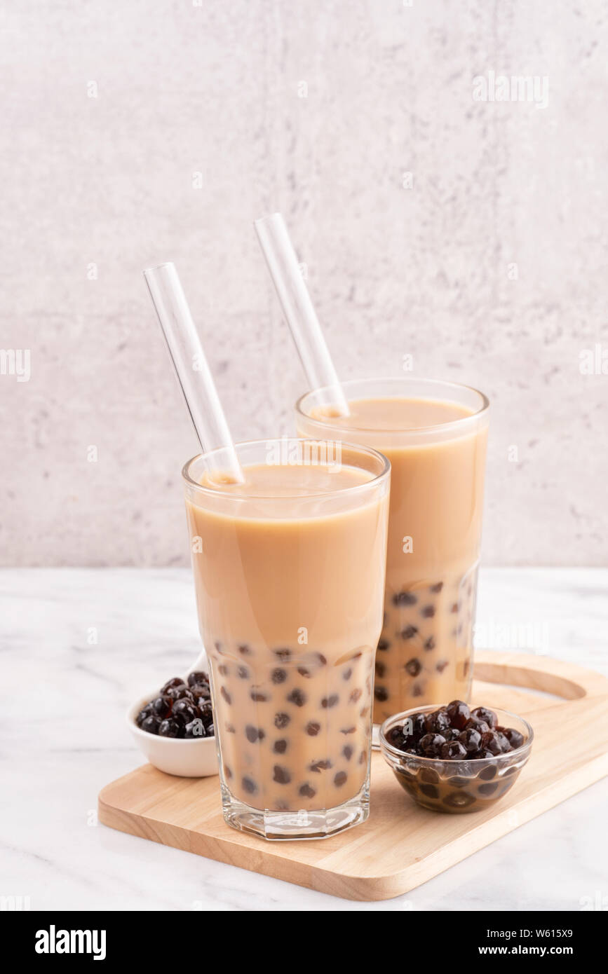 Tapioca pearl ball bubble milk tea, popular Taiwan drink, in drinking glass  with straw on marble white table and wooden tray, close up, copy space  Stock Photo - Alamy