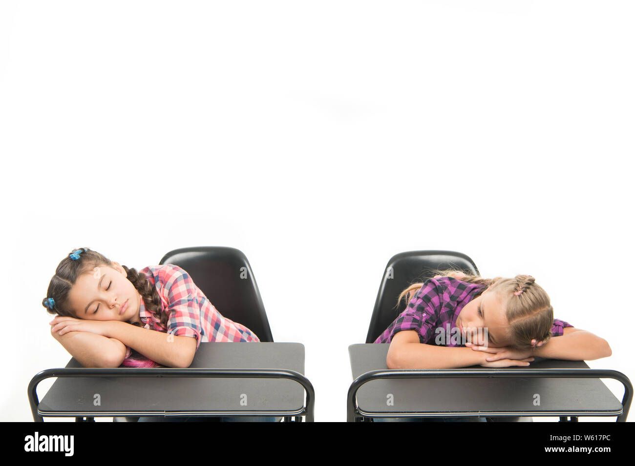 Surviving a boring lesson. Cute school children sleeping at school desks. Little schoolgirls got tired at lesson in primary school. Small girls doing a nap during lesson. Most boring lesson ever. Stock Photo