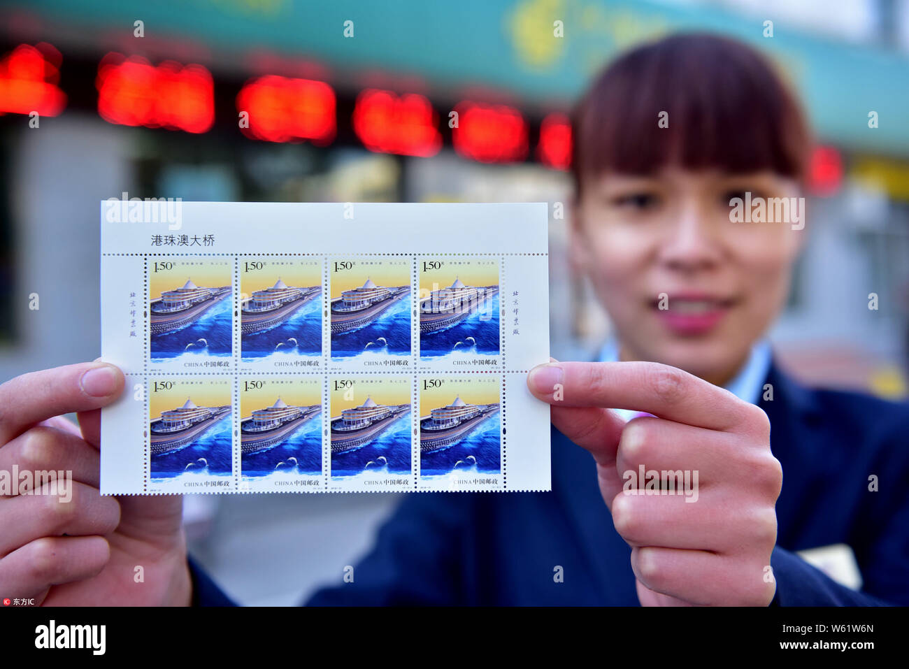 A Chinese employee shows a set of Hong Kong-Zhuhai-Macao Bridge commemorative stamps issued by China Post in Xinle city, north China's Hebei province, Stock Photo