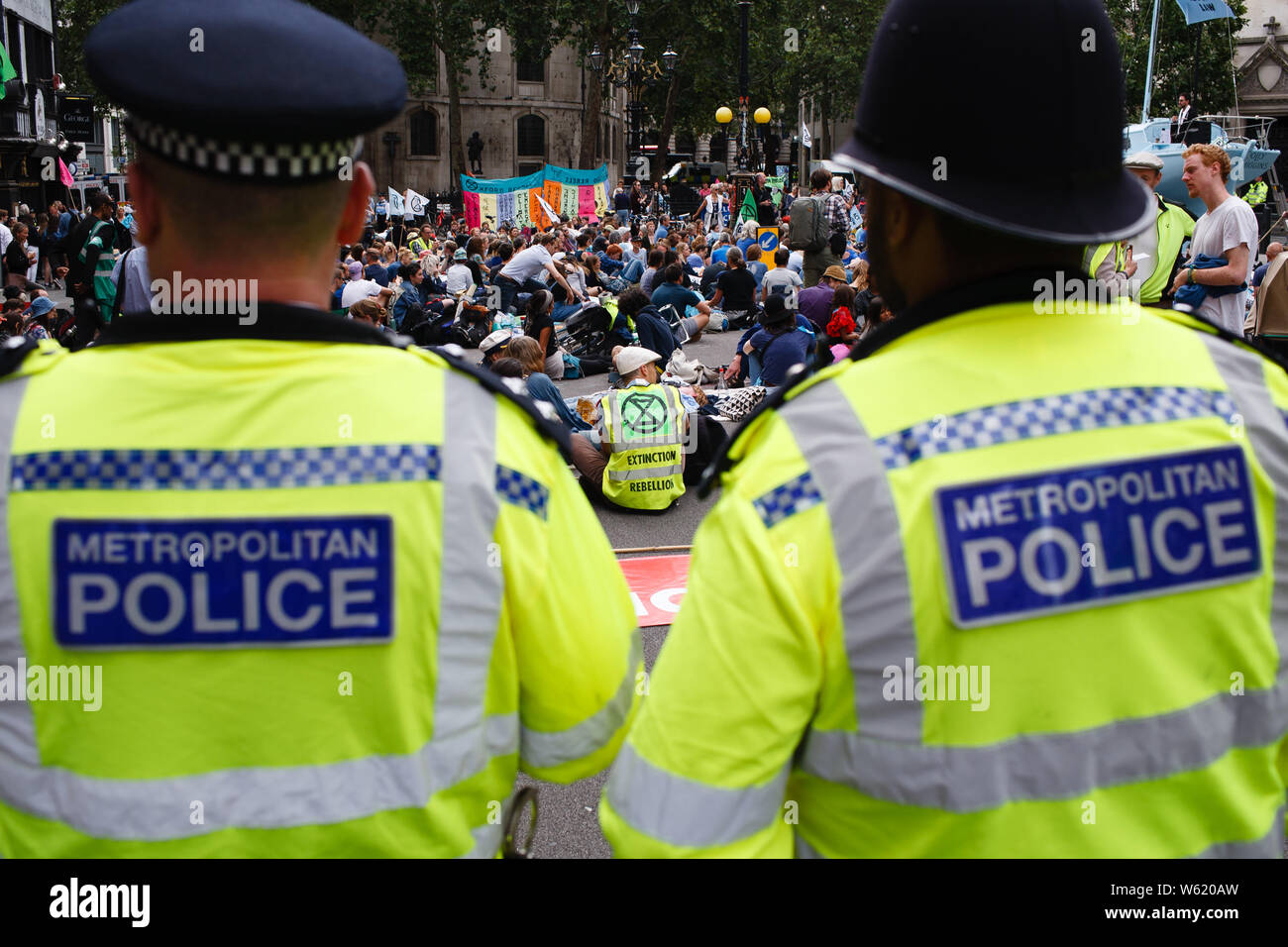 July 15, 2019, London, United Kingdom: Police officers keep watch as members and supporters of climate change activist group Extinction Rebellion take part in the opening day of the group's 'Summer Uprising' demonstration outside the Royal Courts of Justice in London. Demonstrations were also held in Bristol, Cardiff, Leeds and Glasgow. Among their demands for greater action on climate change, protesters are calling for 'ecocide' (i.e. the destruction of ecosystems) to be made a criminal act. The centrepiece of the London protest, a blue boat, the 'Polly Higgins', is named after the late envir Stock Photo