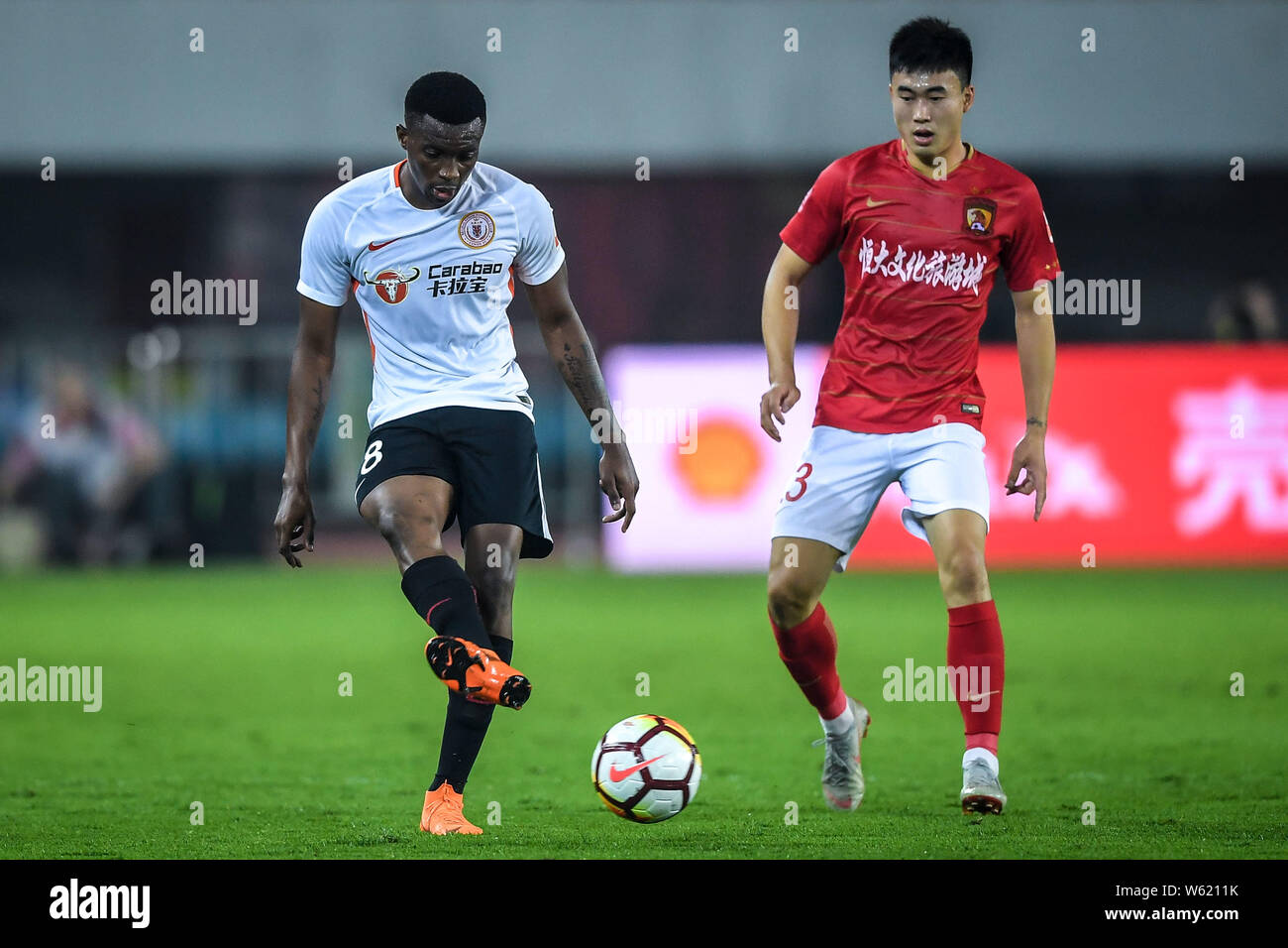 Cameroonian football player Benjamin Moukandjo, right, of Beijing Renhe passes the ball against a player of Guangzhou Evergrande Taobao in their 26th Stock Photo