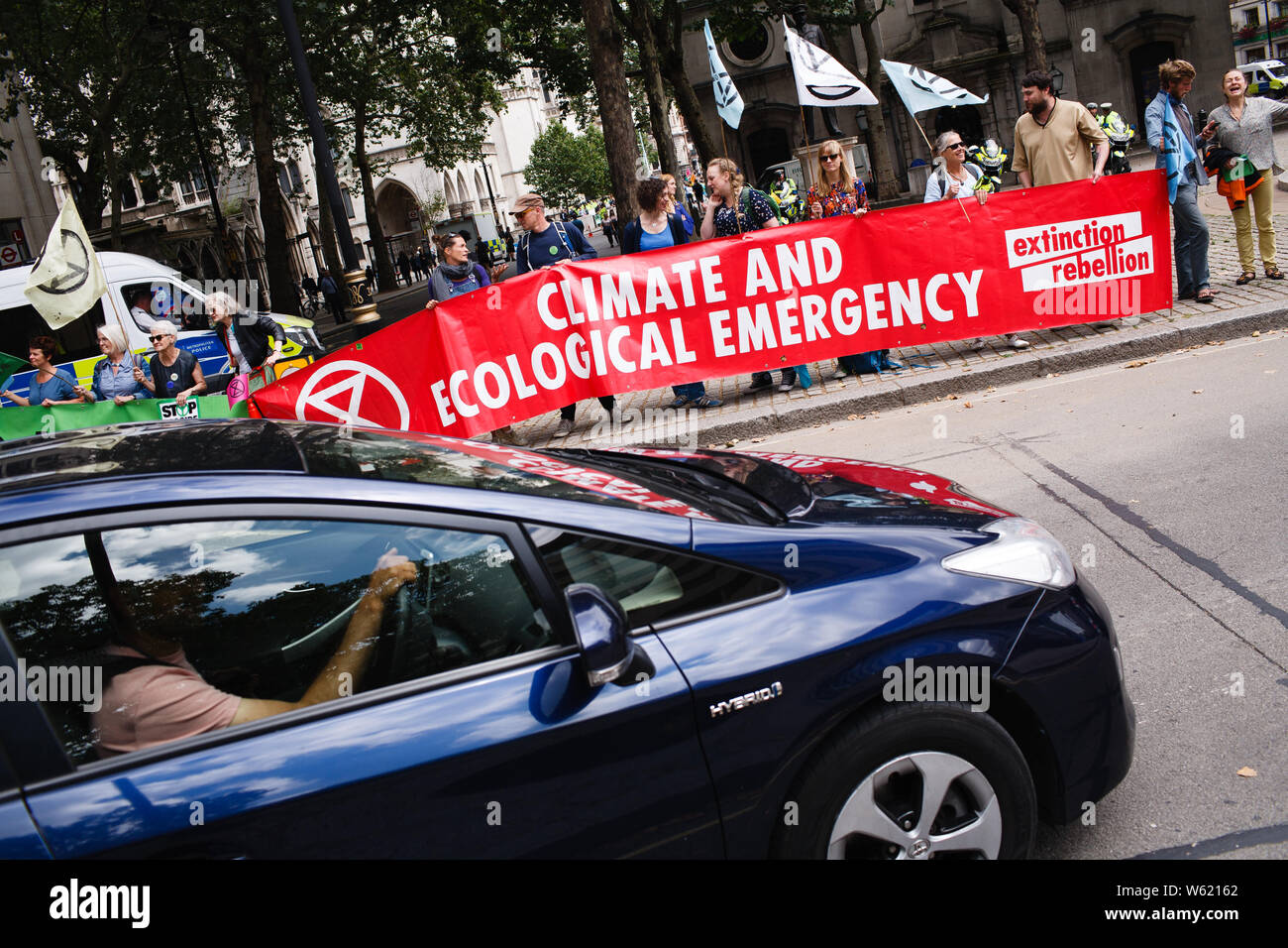 July 15, 2019, London, United Kingdom: Members and supporters of climate change activist group Extinction Rebellion hold a banner at Aldwych on the opening day of the group's 'Summer Uprising' demonstration outside the Royal Courts of Justice in London. Demonstrations were also held in Bristol, Cardiff, Leeds and Glasgow. Among their demands for greater action on climate change, protesters are calling for 'ecocide' (i.e. the destruction of ecosystems) to be made a criminal act. The centrepiece of the London protest, a blue boat, the 'Polly Higgins', is named after the late environmental lawyer Stock Photo