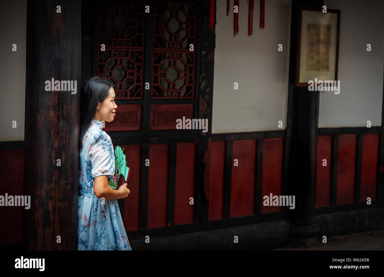 Asian woman in a temple holding a hand fan portrait Stock Photo