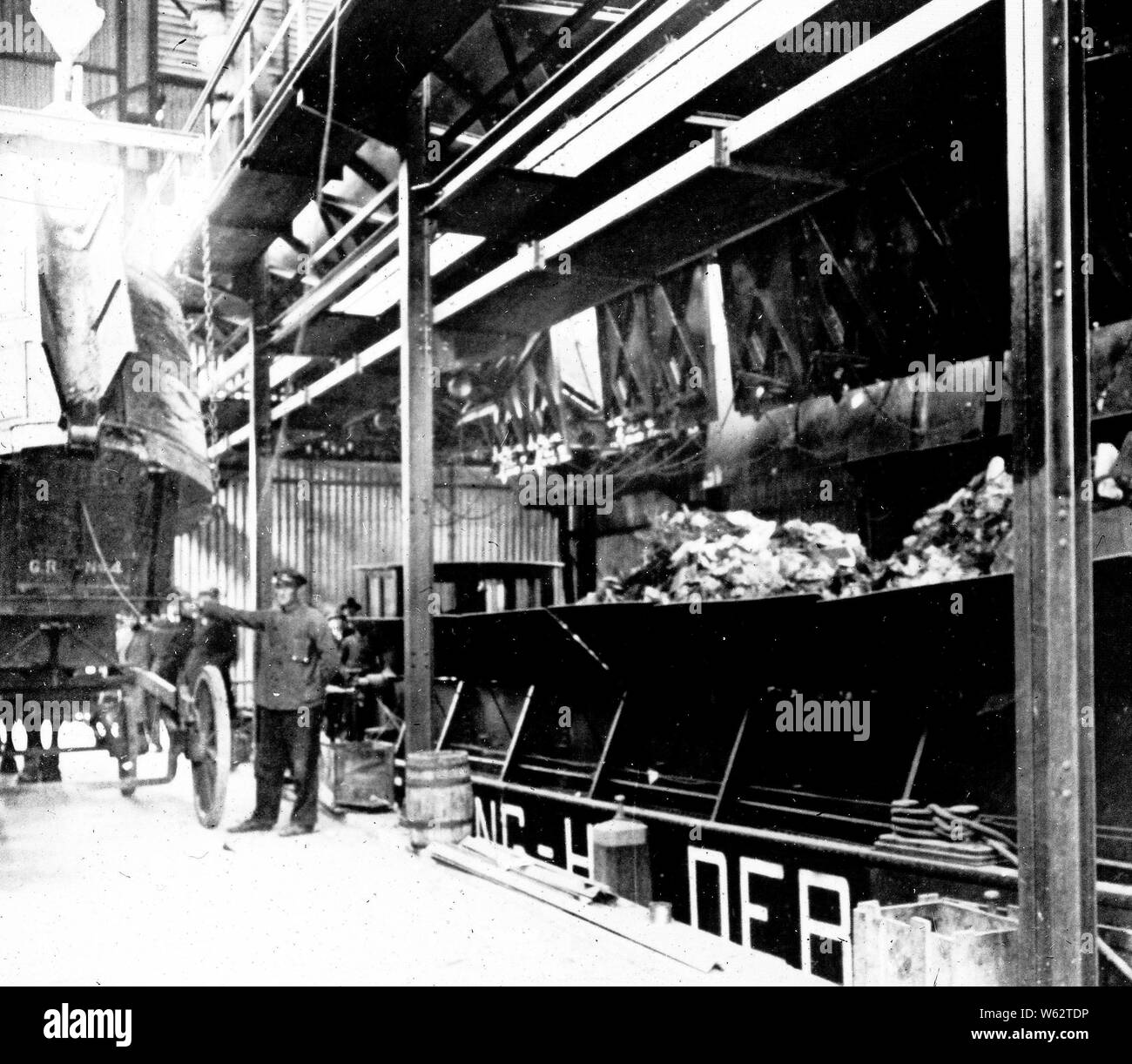 Municipal cleaning of corrugated iron shed interior with a wooden garbage truck and garbage boat ca. 1920 Stock Photo