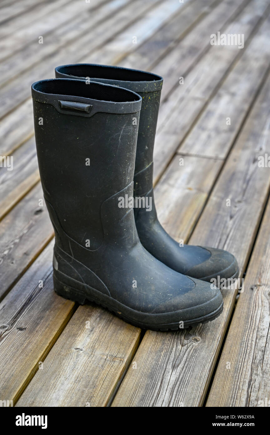 pair of green wellys standing on wooden decking Stock Photo