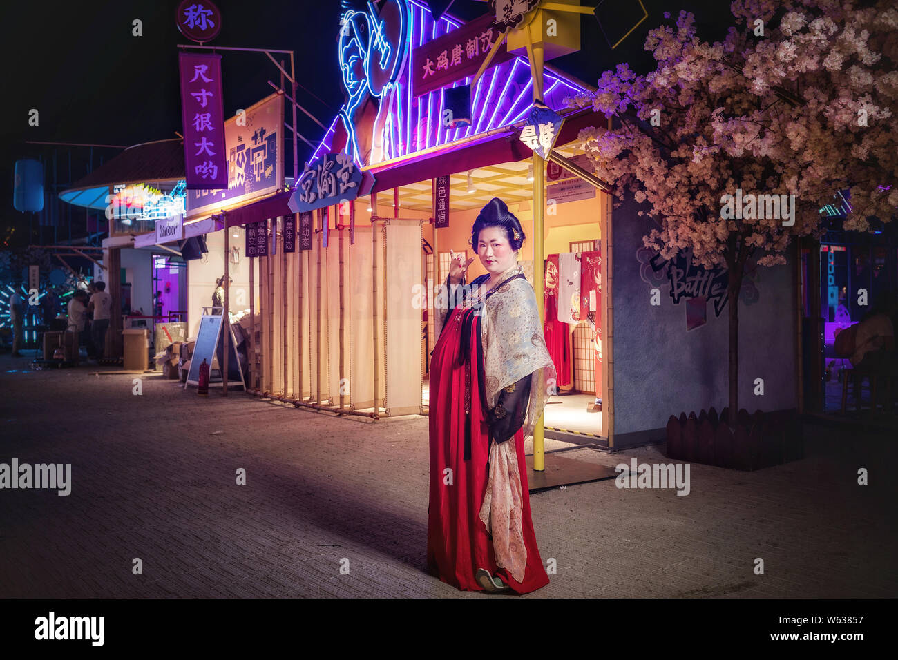 A Chinese woman dressed in Han Chinese clothing that imitates the style of clothes worn by women during the Tang Dynasty (618-907) poses at the stall Stock Photo