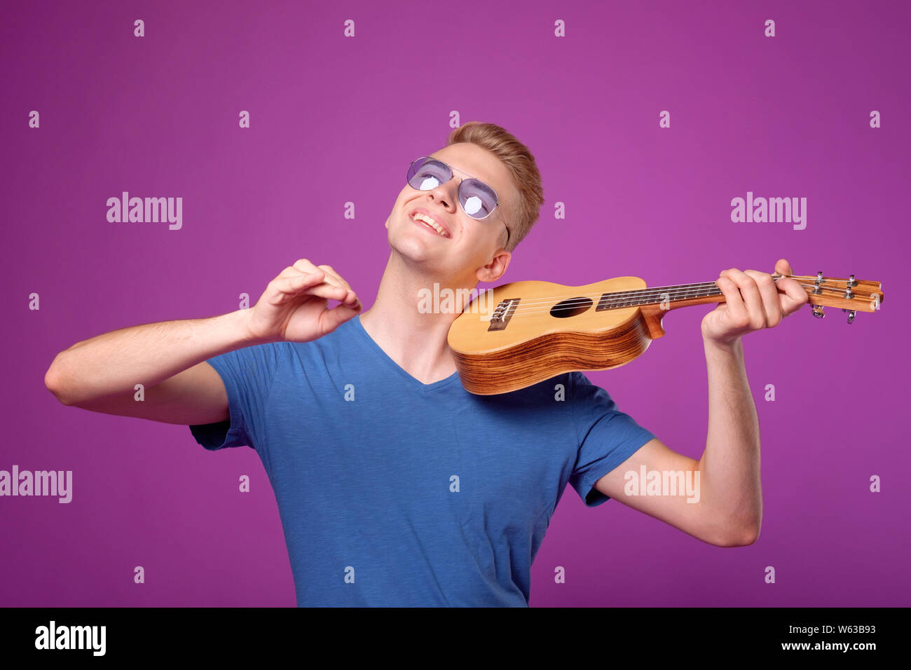 man with ukulele in hands on purple background plays like violin Stock  Photo - Alamy