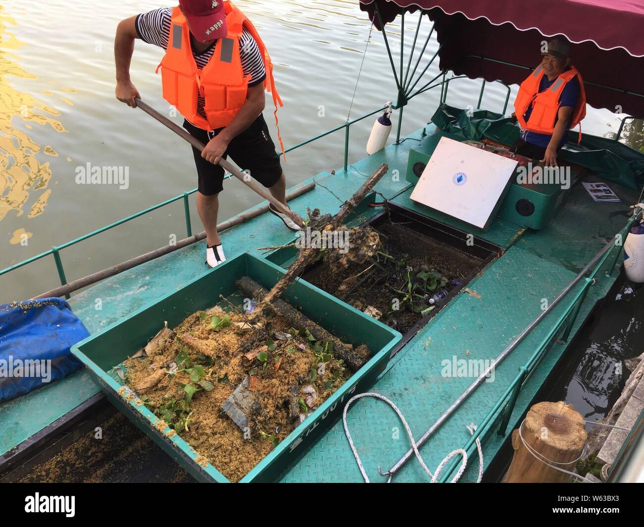 A Chinese worker uses a boat equipped with a new device to collect garbage in a river in Xujiazhan village, Pingyang county, Wenzhou city, east China' Stock Photo