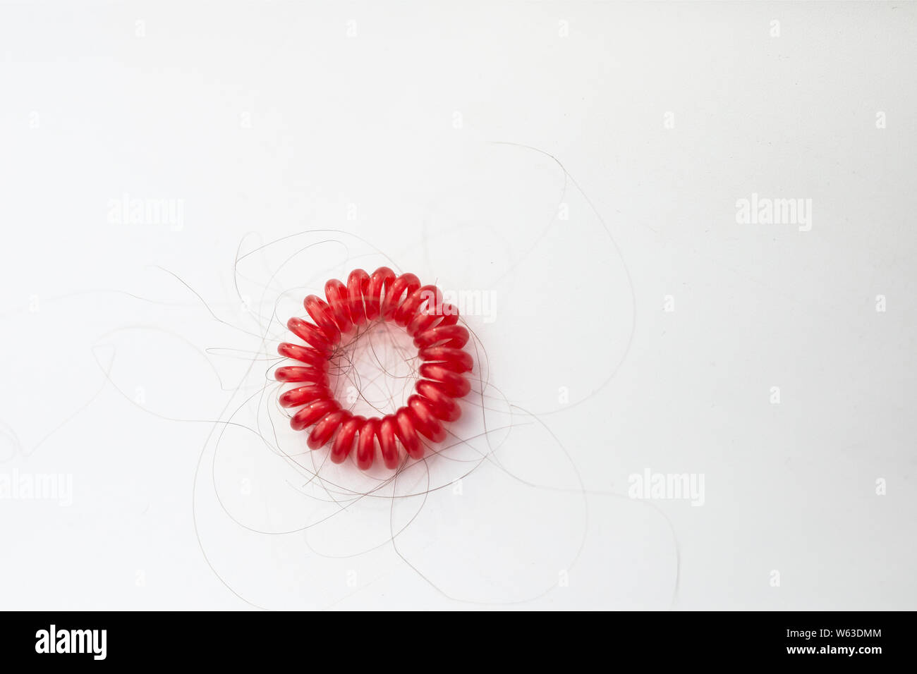 balding concept hair loss, red hair tie with loose hair Stock Photo