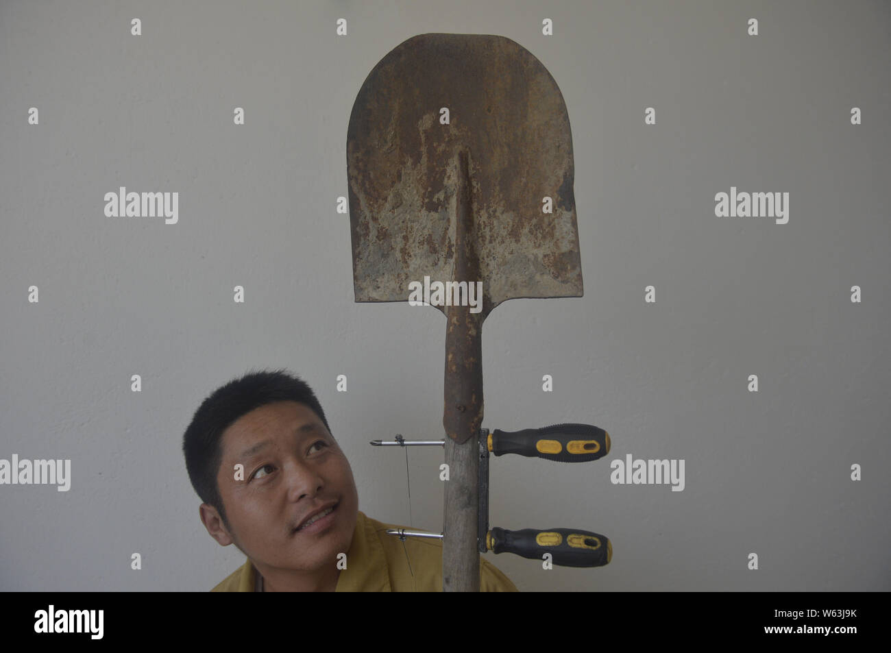 Chinese farmer Zhu Yue plays a self-made Chinese bowed musical instrument 'erhu' from a shovel, a milk powder tin and two screwdrivers in a village in Stock Photo