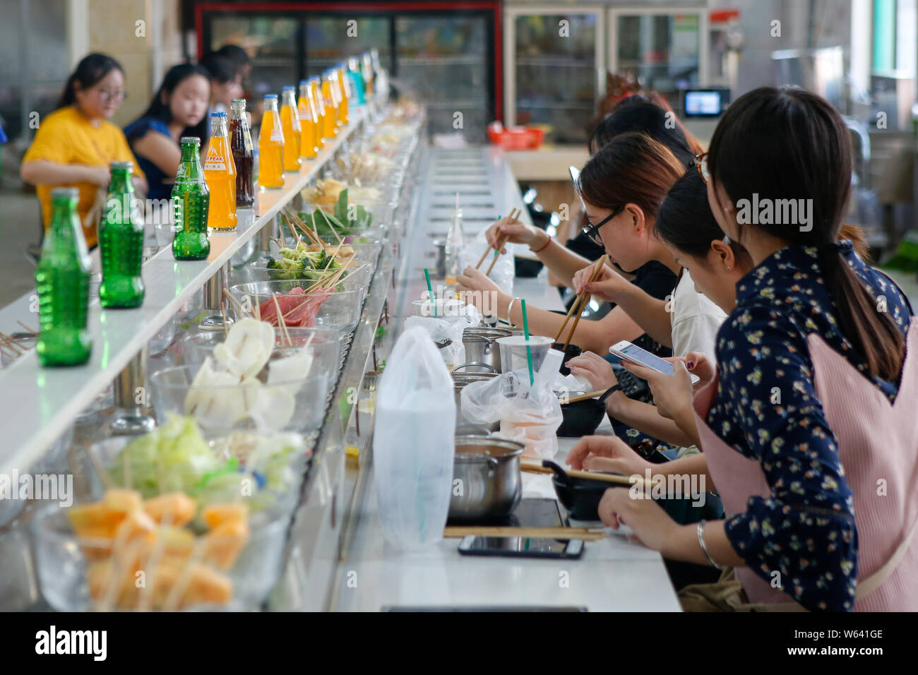 Students eat conveyor belt hotpot, literally "rotation hot pot," at a