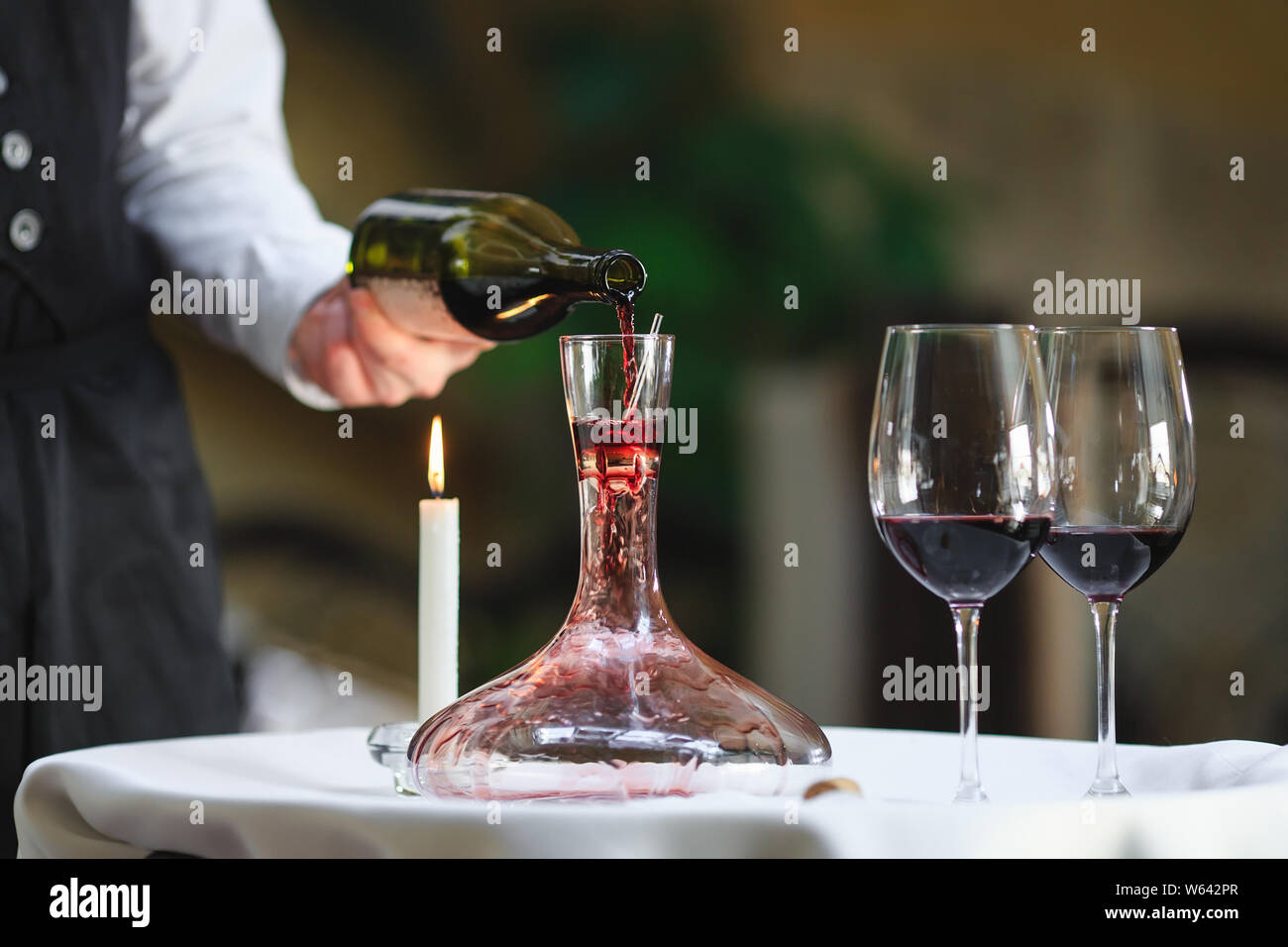A sommelier pouring red wine into decanter Stock Photo Alamy