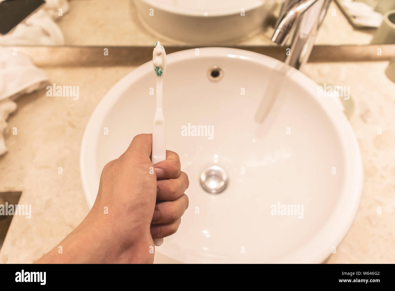 A man hand holding Toothbrush and toothpaste on the sink modern in bathroom. Stock Photo
