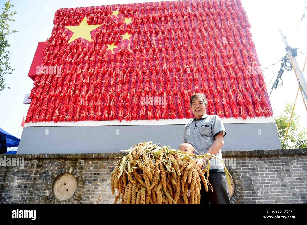 A local man poses with a giant Chinese national flag made of harvested chilies in Mengjin county, Luoyang city, central China's Henan province, 21 Sep Stock Photo