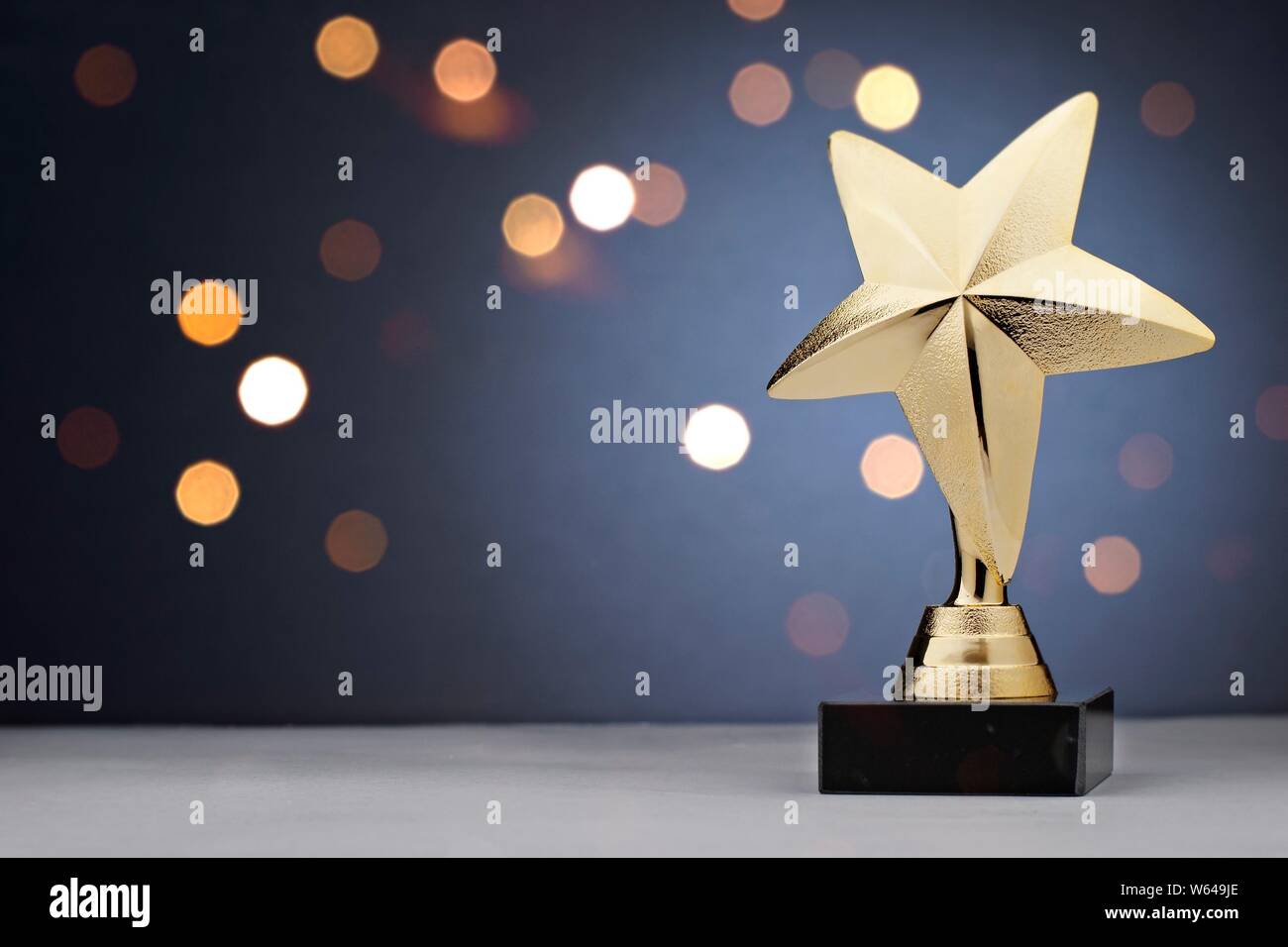 Gold star trophy for a winner or champion of a competition or sporting  event placed to the side against a bokeh of sparkling lights with copy  space Stock Photo - Alamy