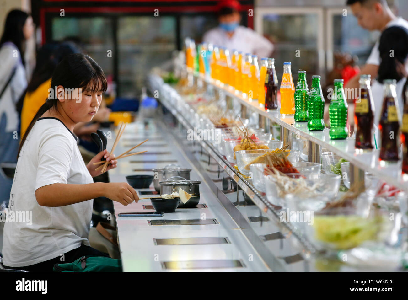 Students eat conveyor belt hotpot, literally "rotation hot pot," at a