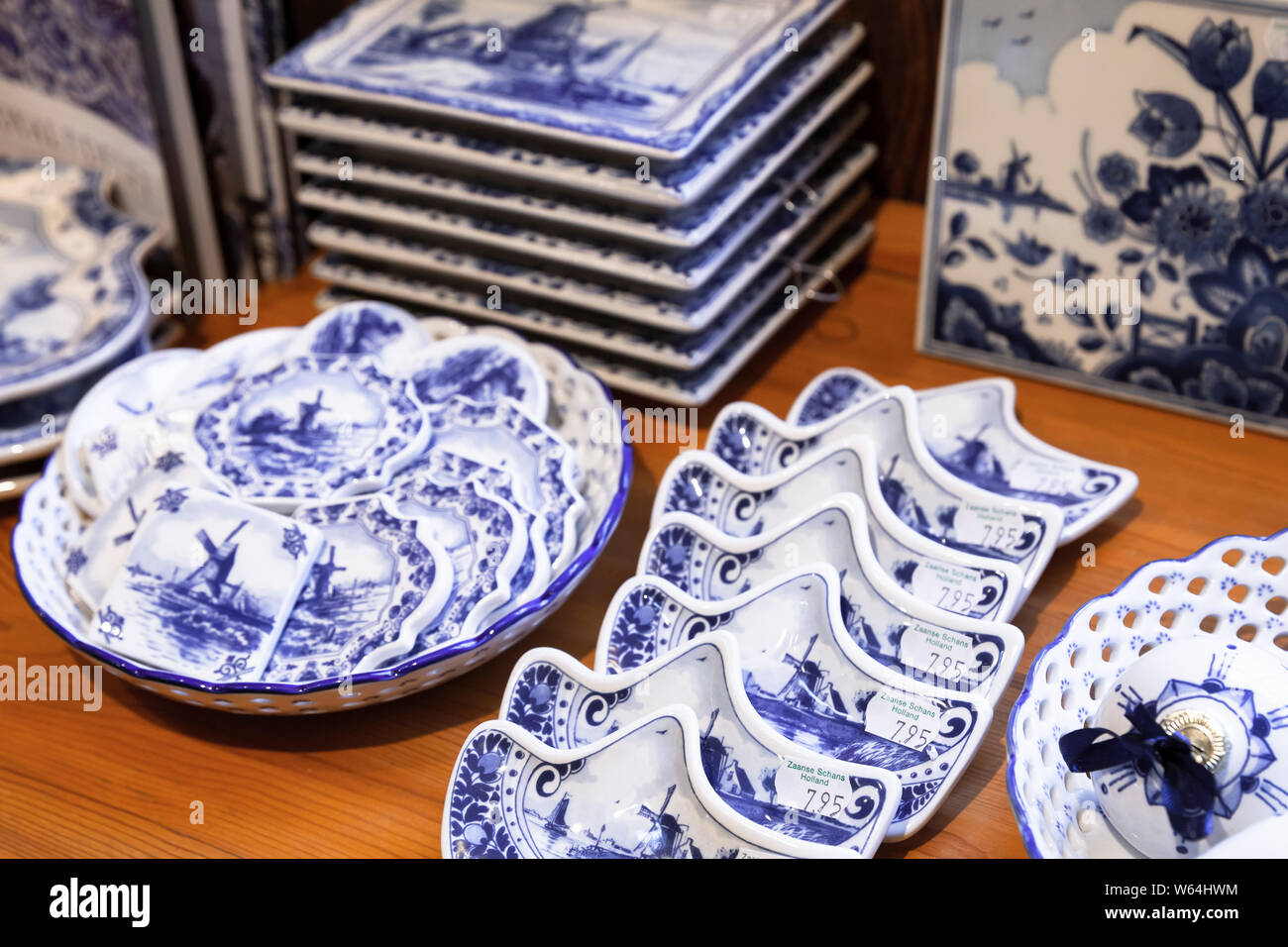 Zaanse Schans, Netherlands - February 25, 2017: White ceramic dishes with traditional blue Dutch paintings are on wooden counter in tourist souvenir s Stock Photo