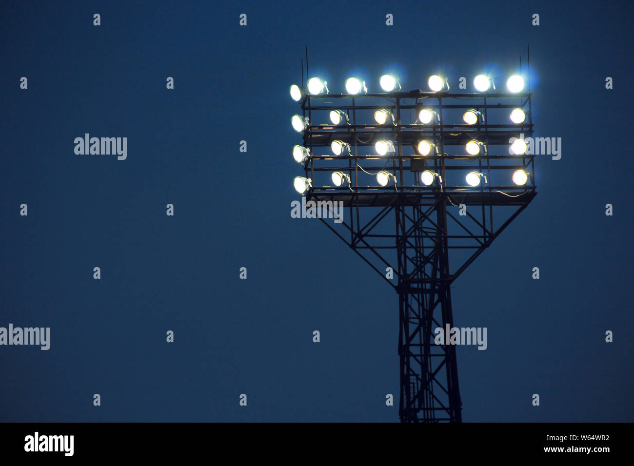 Spotlights illuminate football field during match. Lighting equipment for stadiums. Powerful lighting in stadium Stock Photo