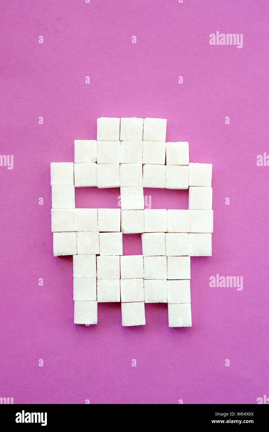 Sugar cubes laid out in shape of skull on purple background. Sugar is