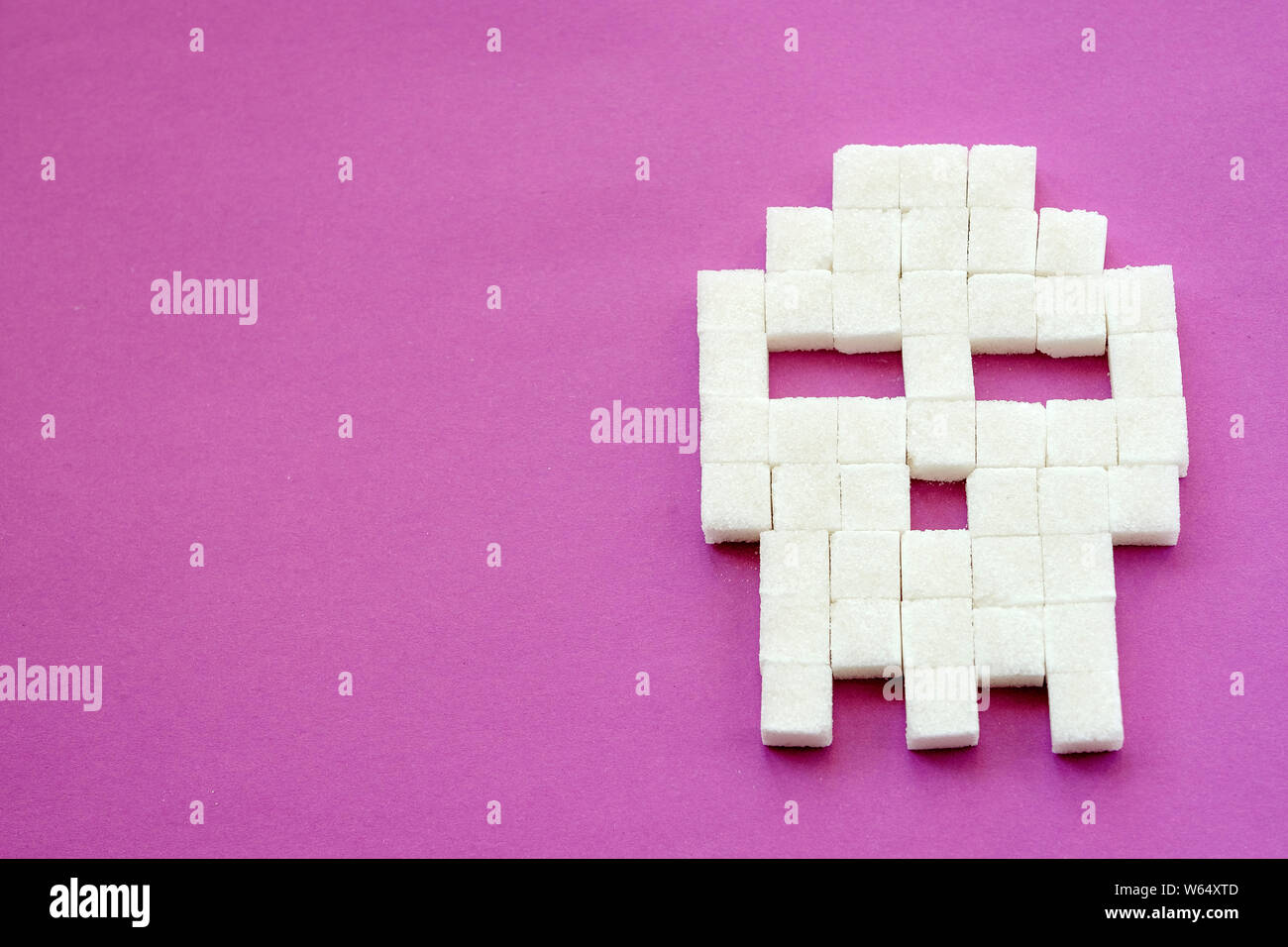 Sugar cubes laid out in shape of skull on purple background. Sugar is white Death. Diabetes, sugar disease, unhealthy food, diet concept. Copy space Stock Photo