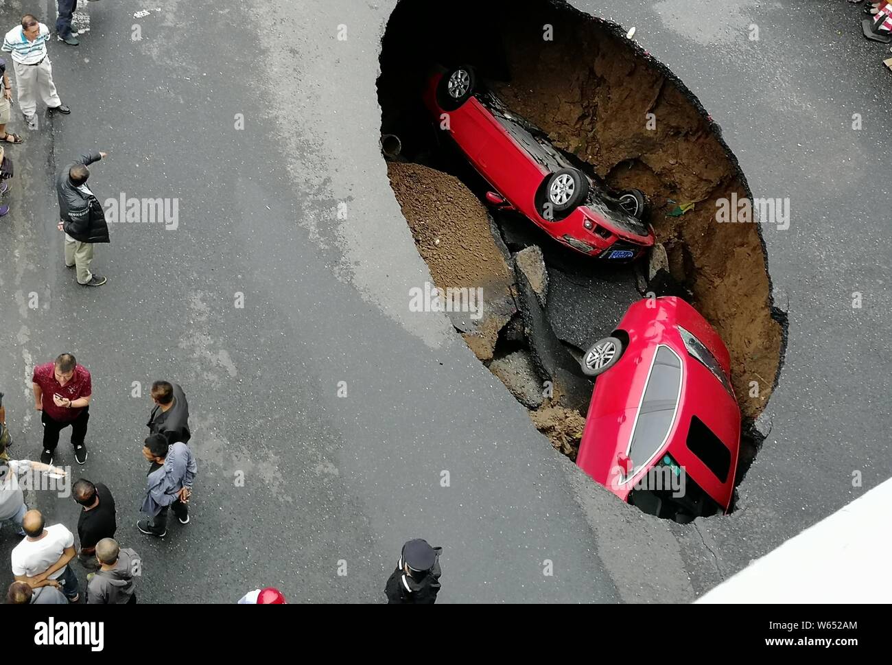 Two vehicles are trapped in a sink hole caused by the collapse of the ground in Harbin city, northeast China's Heilongjiang province, 4 August 2018. Stock Photo