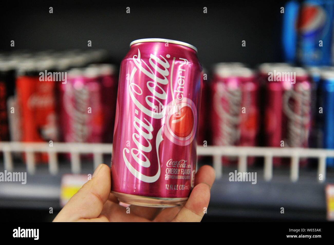 --FILE--A customer shops for a tin of Coca-Cola coke at a supermarket in Qingdao city, east China's Shandong province, 5 April 2018.   US soda and bee Stock Photo