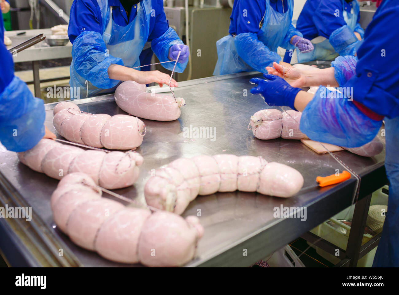 Butchers processing sausages at the meat factory. Stock Photo