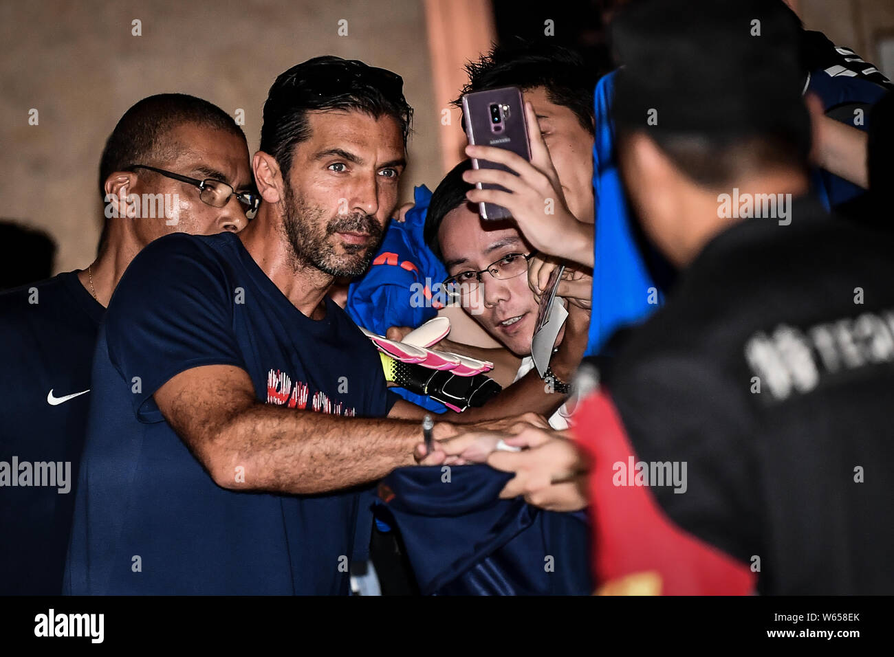 Goalkeeper Gianluigi Buffon of Paris Saint-Germain signs autographs for fans as he and teammates leave the hotel for an event for Trophee des Champion Stock Photo