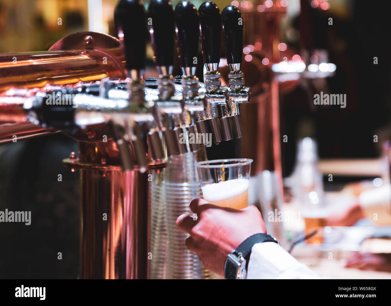 Bartender pouring draft beer in the bar, Barman hand at beer tap pouring draught lager beer serving in a restaurant or pub Stock Photo