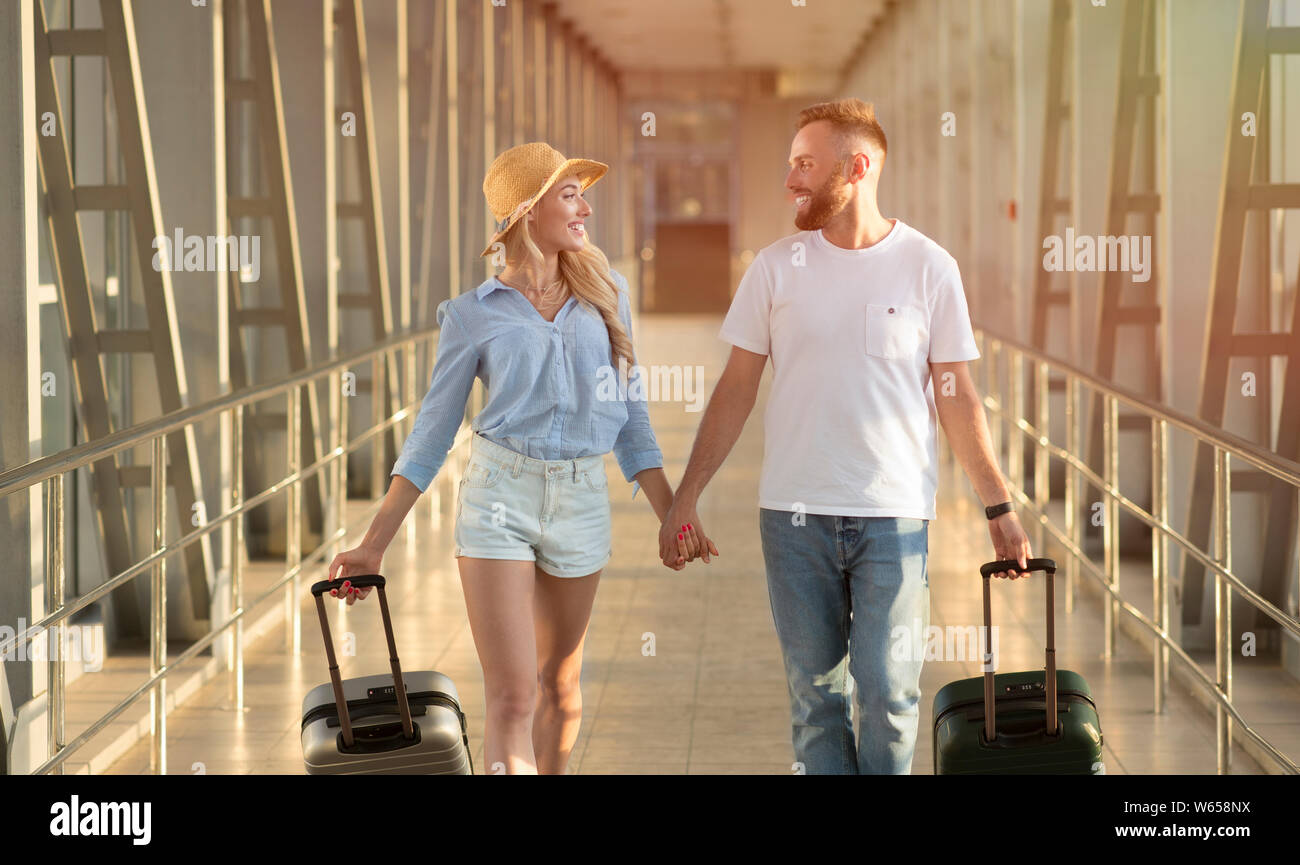 Happy couple going in airport terminal with suitcases Stock Photo - Alamy