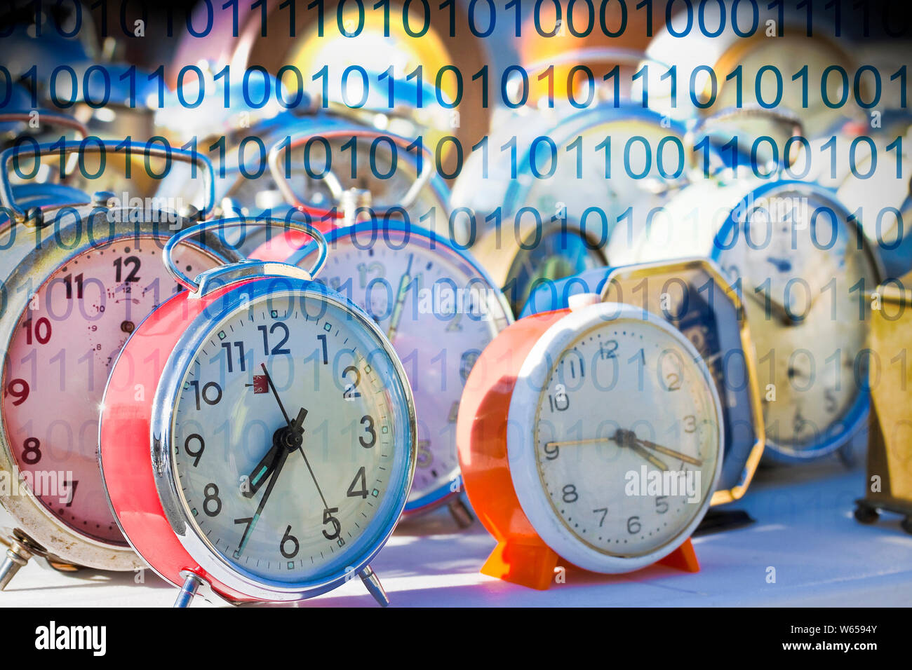 It's time to protect your data - Concept image with old colored metal table clocks with binary code Stock Photo