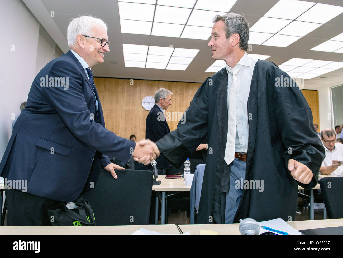31 July 2019, North Rhine-Westphalia, Münster: Jürgen Resch (l), federal managing director of the German environmental assistance, welcomes the attorney Remo Klinger before the negotiation. The Higher Administrative Court of North Rhine-Westphalia is hearing the action brought by Deutsche Umwelthilfe (German Environmental Aid) against the city of Aachen for the continuation of the Cologne district government's air pollution control plans. The aim is to take measures to ensure that the limit values for nitrogen dioxide are complied with as quickly as possible. Photo: Guido Kirchner/dpa Stock Photo