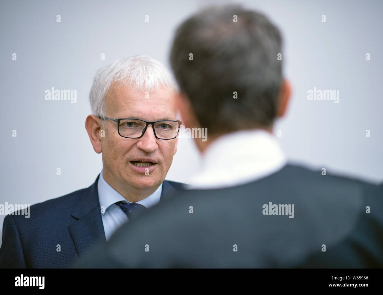 31 July 2019, North Rhine-Westphalia, Münster: Jürgen Resch (l), Federal Managing Director of Deutsche Umwelthilfe, and lawyer Remo Klinger talk to each other before the trial begins. The Higher Administrative Court of North Rhine-Westphalia is hearing the action brought by Deutsche Umwelthilfe (German Environmental Aid) against the city of Aachen for the continuation of the Cologne district government's air pollution control plans. The aim is to take measures to ensure that the limit values for nitrogen dioxide are complied with as quickly as possible. Photo: Guido Kirchner/dpa Stock Photo