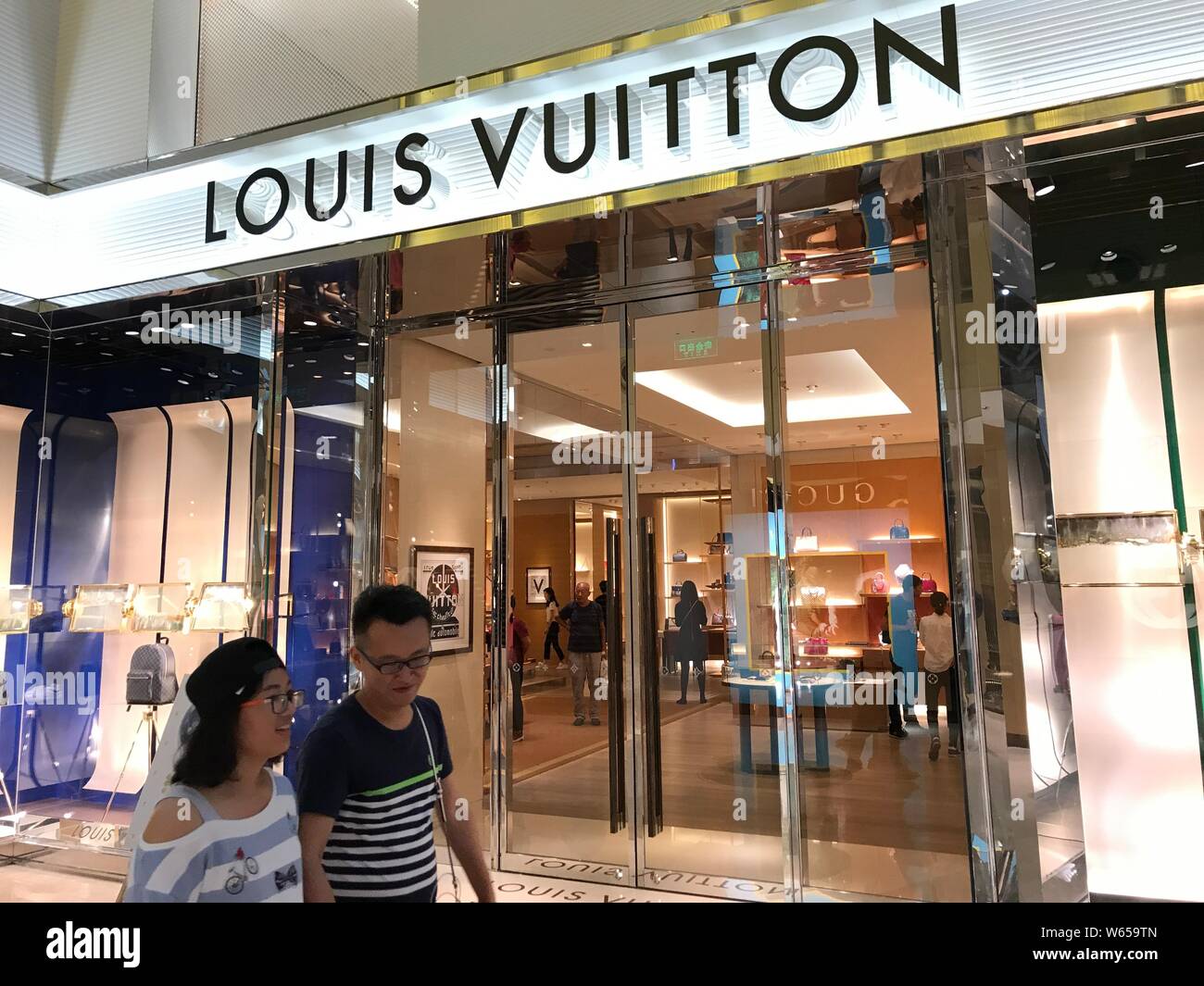 FILE--Customers walk past a boutique of Louis Vuitton (LV) in Shanghai,  China, 3 October 2017. Global luxury brands from Prada to LVMH are invest  Stock Photo - Alamy