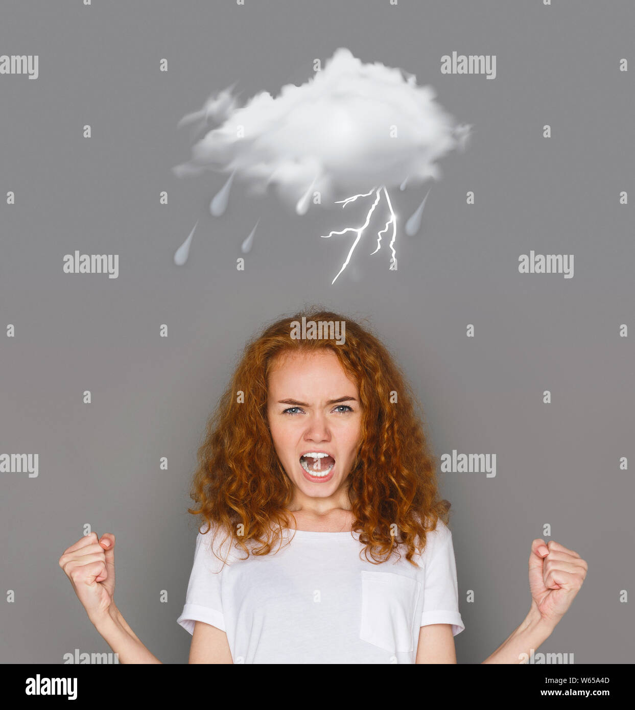 Lightning emotion of redhaired girl crying on gray background Stock Photo