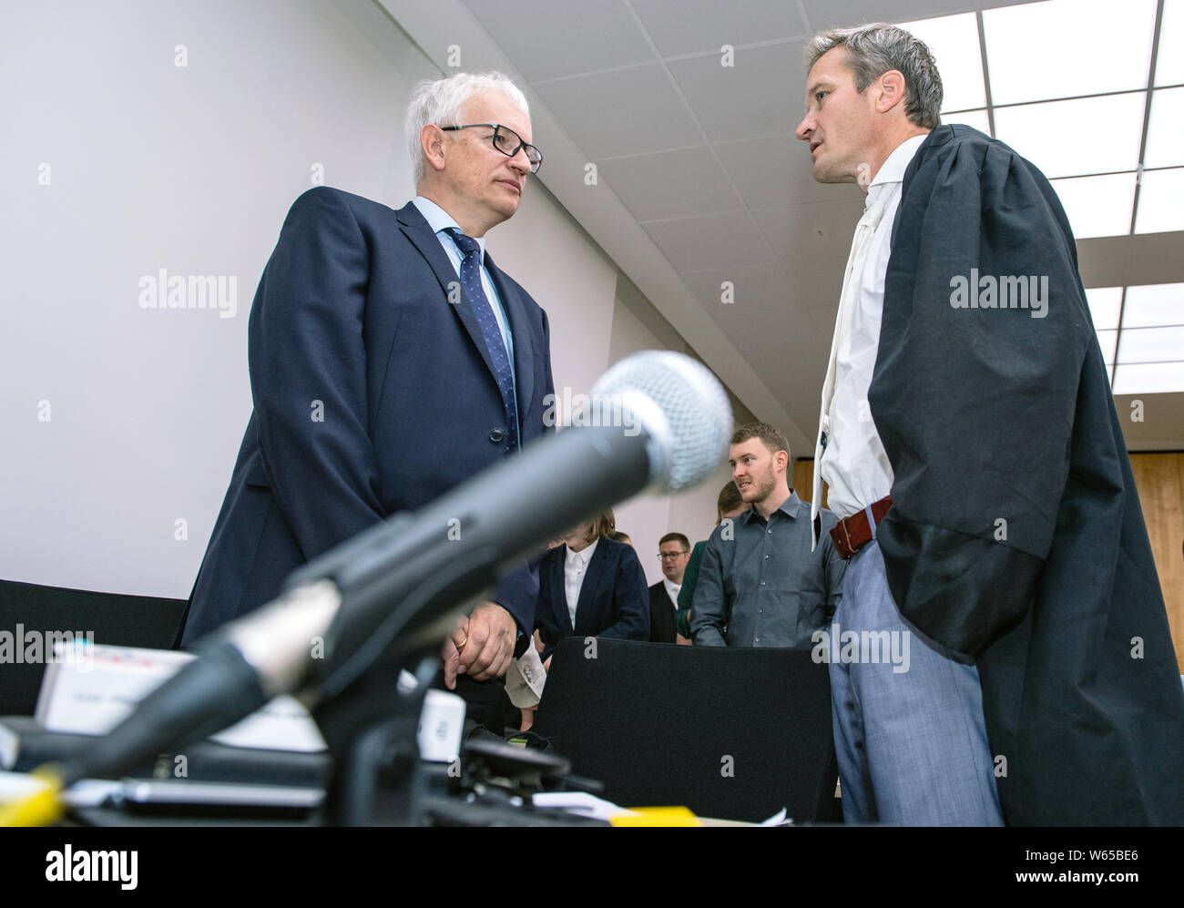 31 July 2019, North Rhine-Westphalia, Münster: Jürgen Resch (l), Federal Managing Director of Deutsche Umwelthilfe, and lawyer Remo Klinger talk to each other before the trial begins. The Higher Administrative Court of North Rhine-Westphalia is hearing the action brought by Deutsche Umwelthilfe (German Environmental Aid) against the city of Aachen for the continuation of the Cologne district government's air pollution control plans. The aim is to take measures to ensure that the limit values for nitrogen dioxide are complied with as quickly as possible. Photo: Guido Kirchner/dpa Stock Photo