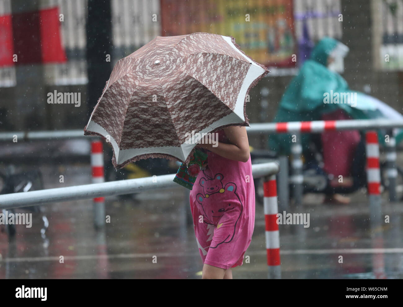 A pedestrian shielding herself with an umbrella braves strong wind and heavy downpour caused by Typhoon Rumbia, the 18th typhoon of the year, in Nanto Stock Photo