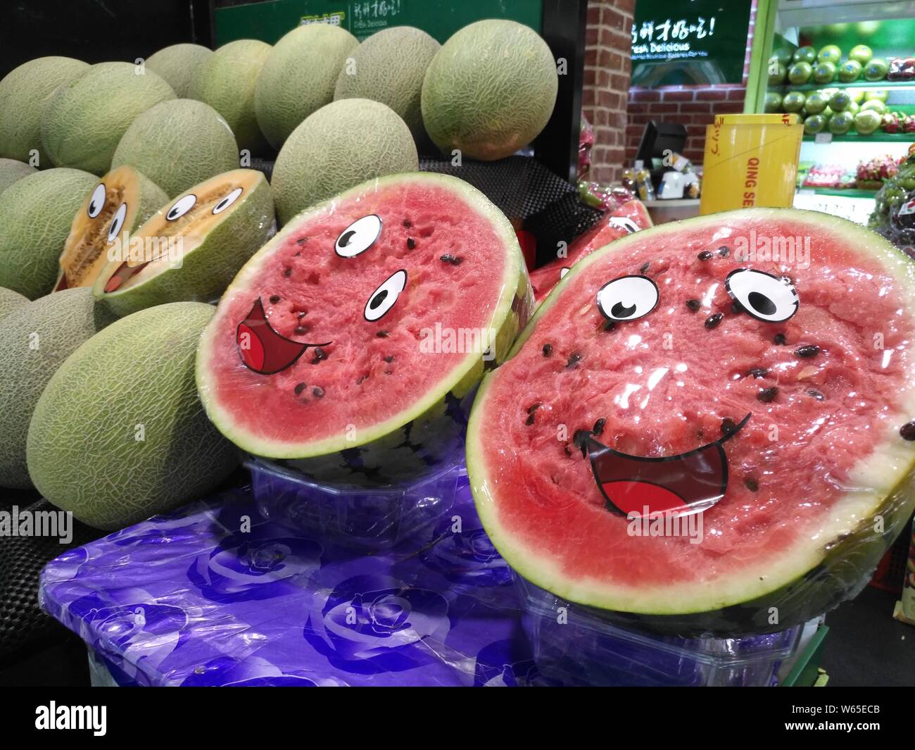 Watermelons covered with smiling cartoon faces on the plastic wrap are