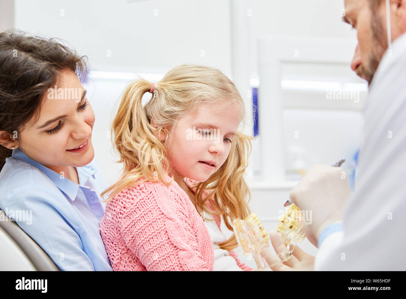 Pediatric dentist with mother and child as anxiety patient in conversation before the examination Stock Photo