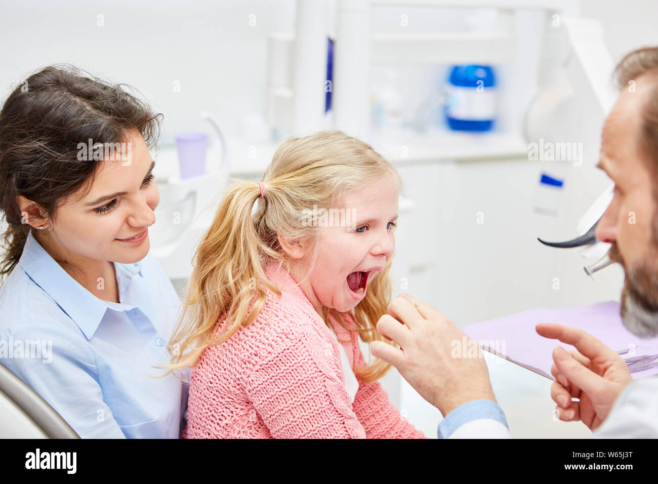 Dentist in the consultation with mother and child builds confidence on before the examination Stock Photo
