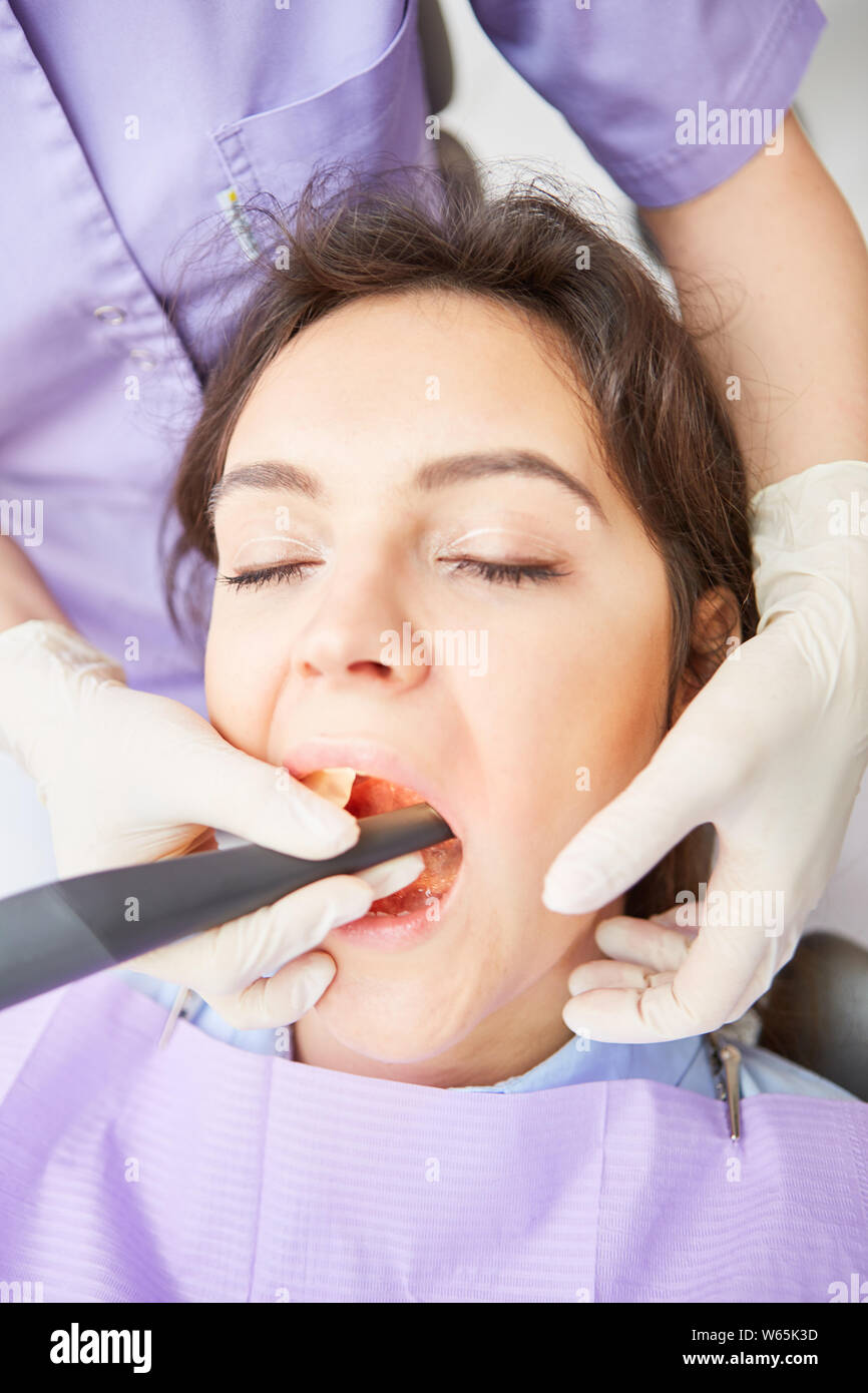 Dentist treating a tooth decay or removing tartar with the drill Stock